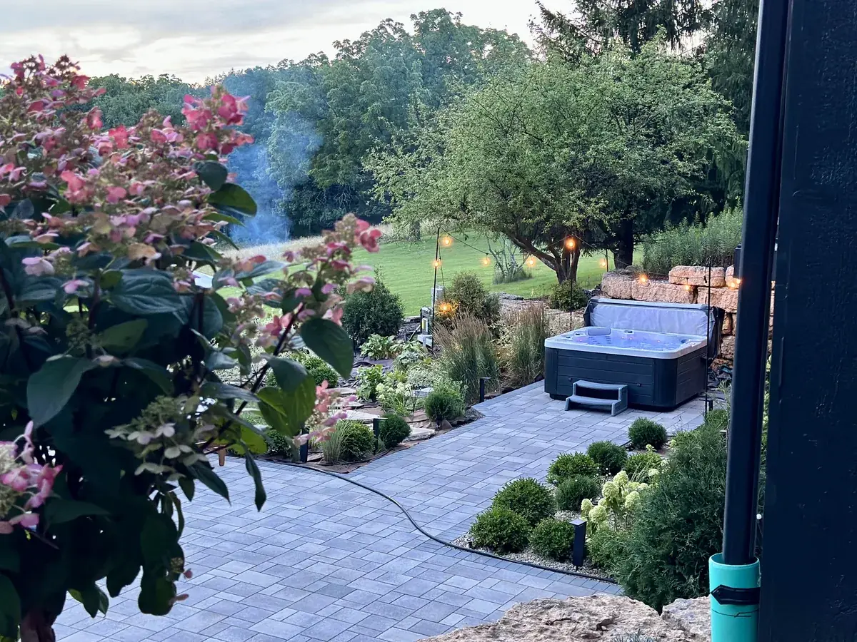 The hot tub on the stone patio at dusk under string lights