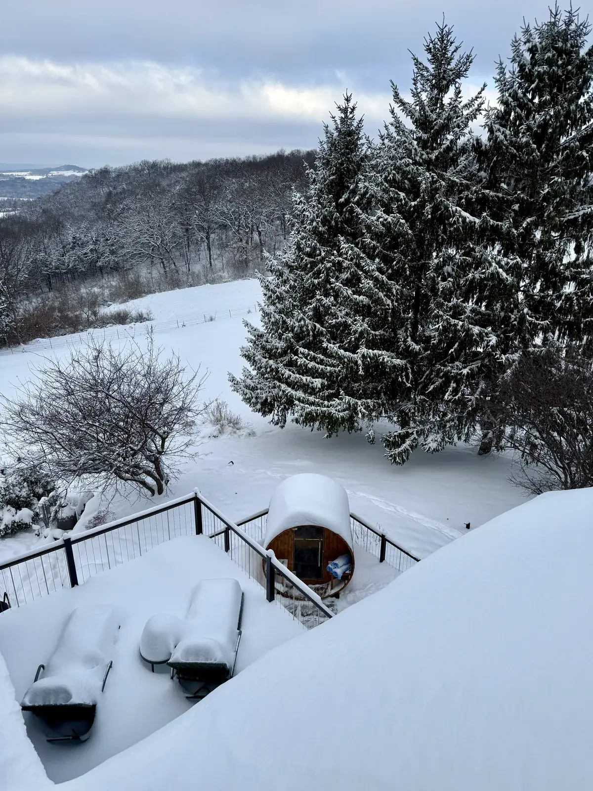 The cedar barrel sauna on the deck after a snowfall